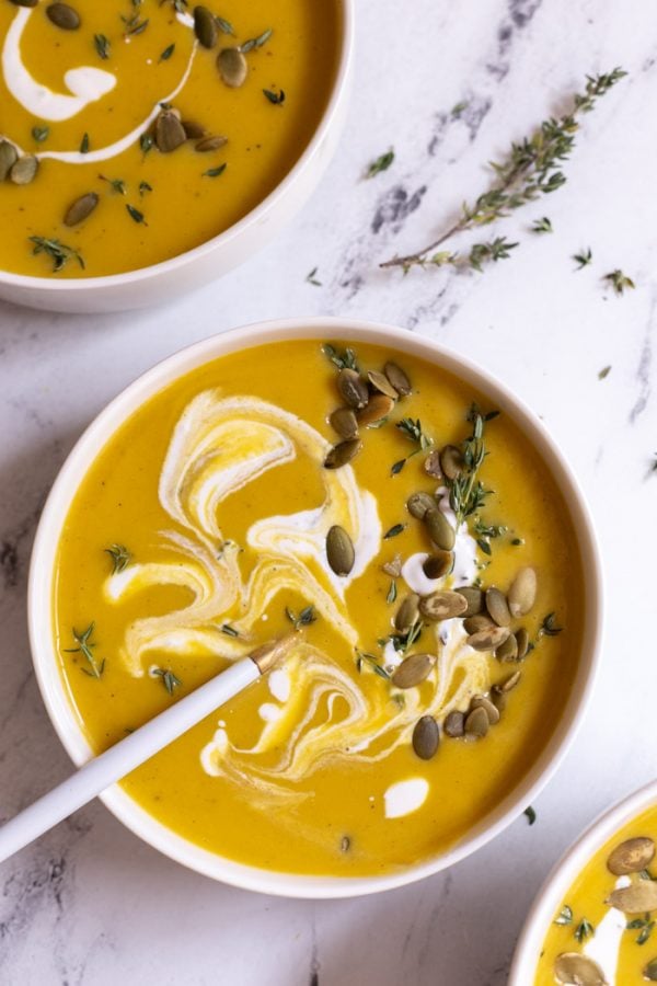 butternut squash soup with cream on top on a marble board