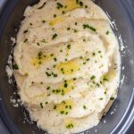 crock pot mashed potatoes topped with butter and garnished with fresh parsley