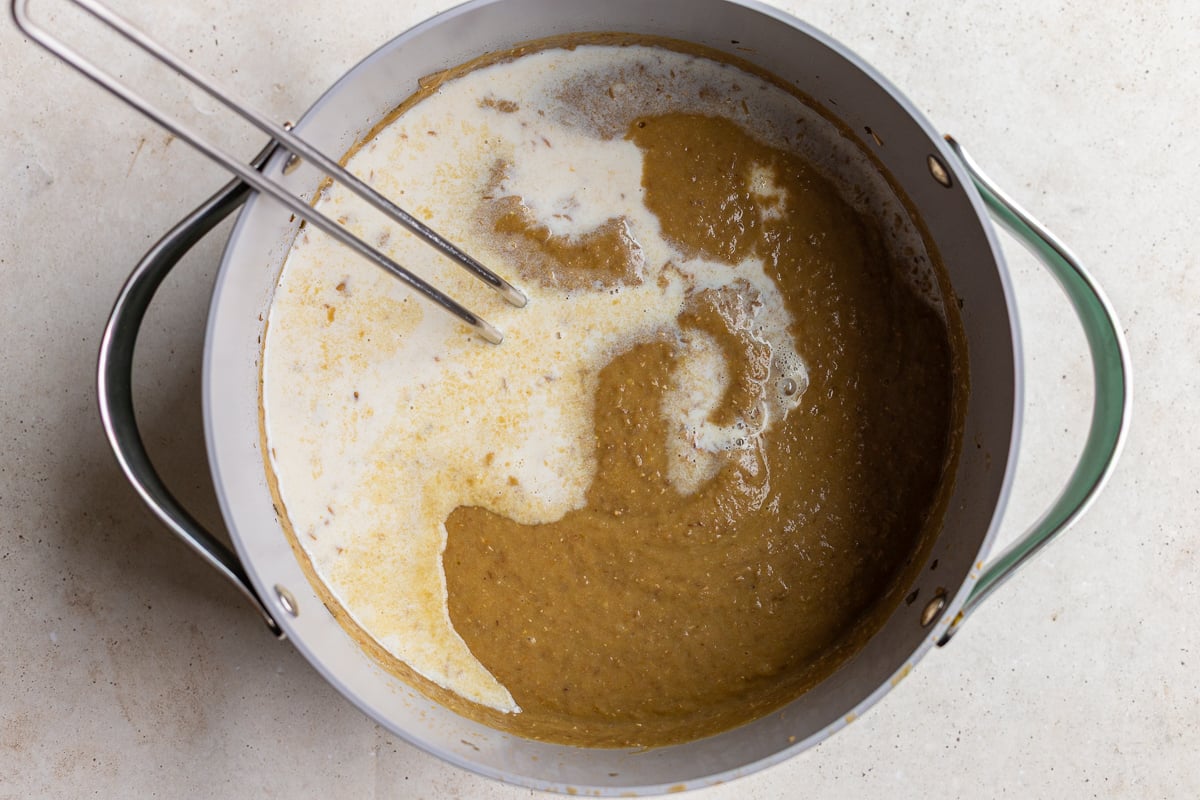 creamy lentil soup in a large pot with milk just poured in before being stirred