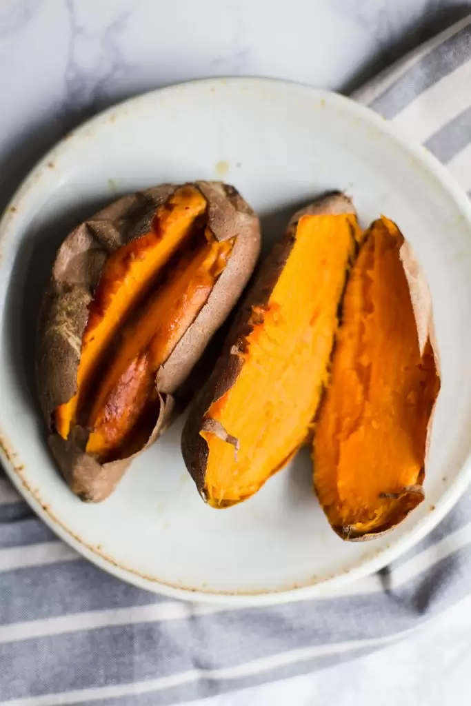 2 baked sweet potatoes cut open on a plate
