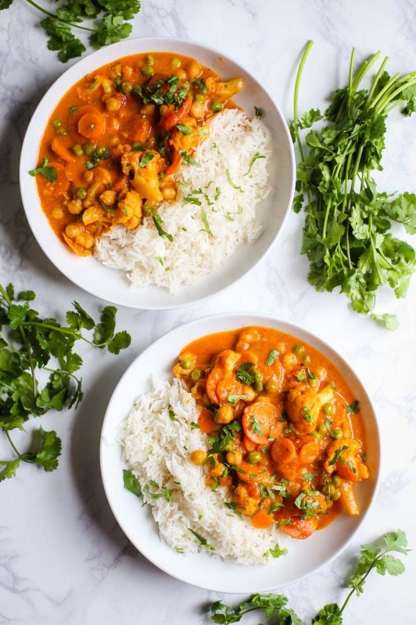 2 cuencos de tikka masala y arroz blanco sobre un fondo de mármol