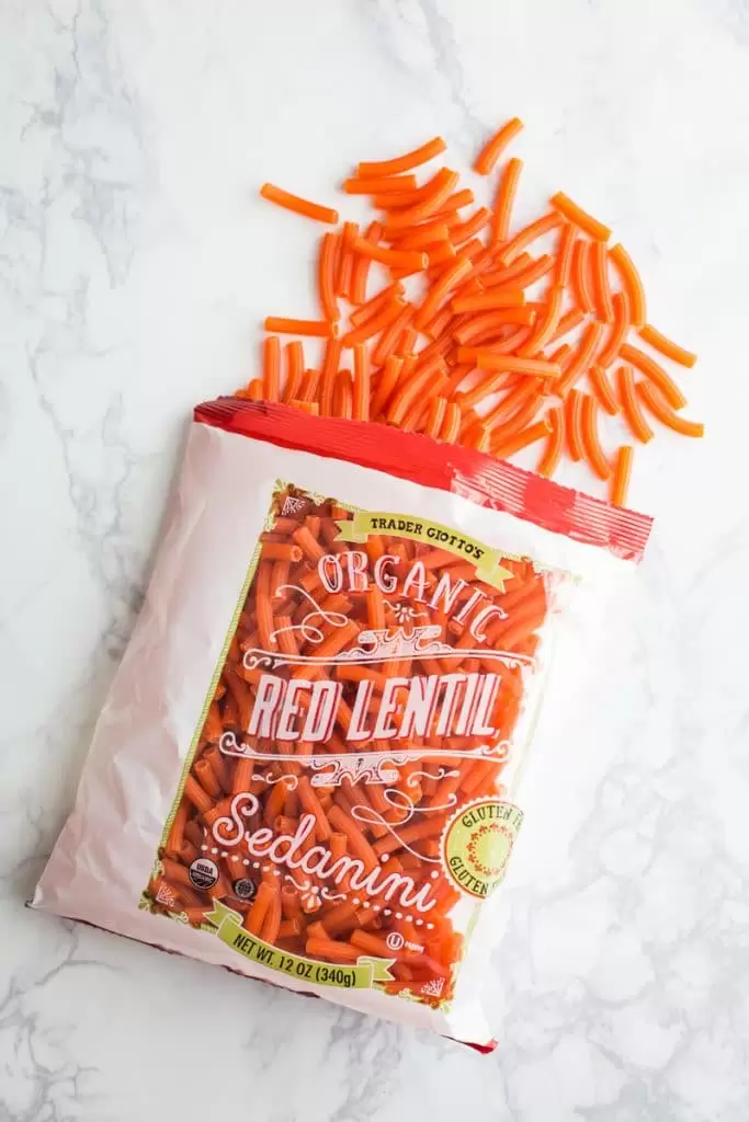 bag o trader joes organic red lentil pasta spilling out of the bag. sitting on top of a marble board
