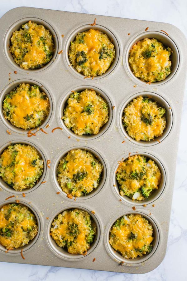 quinoa, cheddar cheese, and broccoli bites in a muffin tin on a marble board