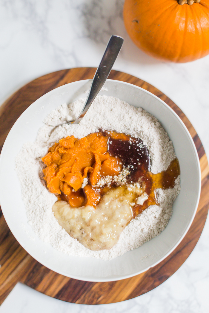 pumpkin bread ingredients in a bowl including flour, pumpkin puree, maple syrup, banana