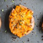 smashed sweet potato round on a baking sheet topped with pepper
