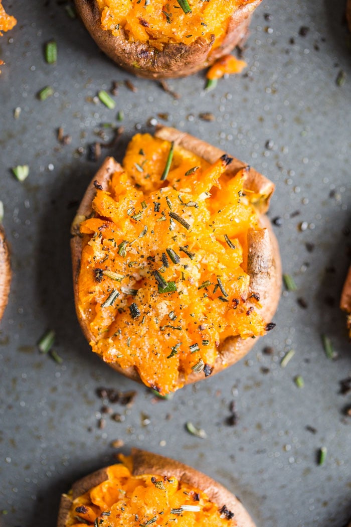 smashed sweet potato round on a baking sheet topped with pepper