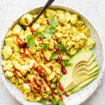 Tofu scramble topped with ketchup and served with avocado.