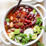 vegan crockpot chili in a white bowl with a spoon