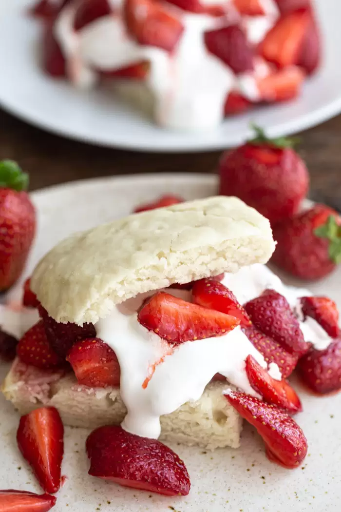 traditional strawberry shortcake topped with whipped cream and quartered strawberries