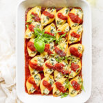 Vegan stuffed shells covered in sauce and garnished with basil.