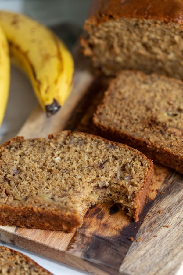 vegan banana bread on a wood board with a bite taken out