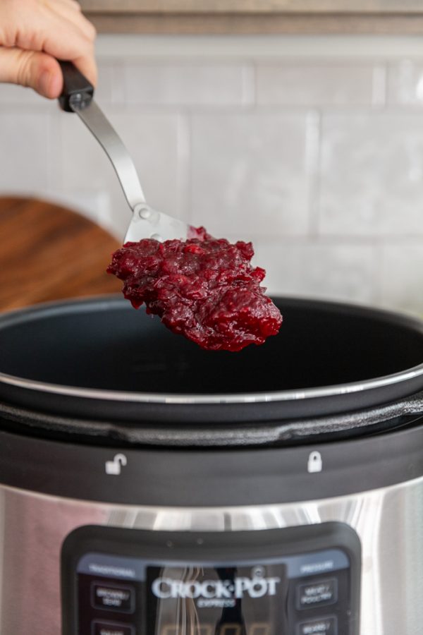 spoonful of cranberry sauce coming out of a pressure cooker