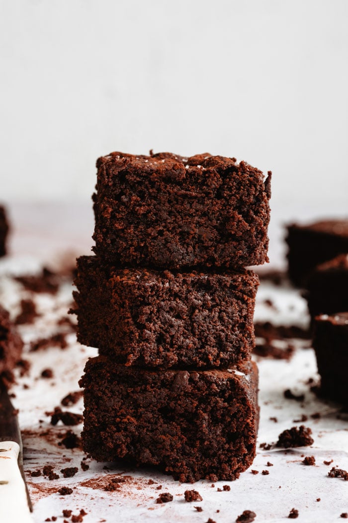 3 vegan brownies stack on top of each other on a white background