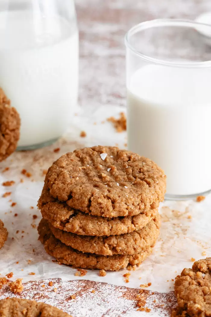 small stack of vegan peanut butter cookies next to a glass of milk