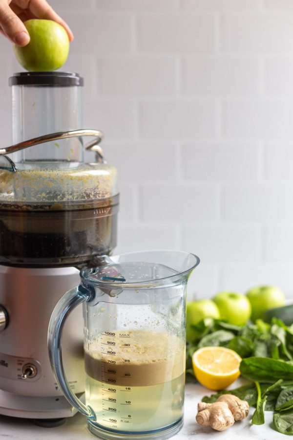 juicer with an apple going in the top to be juiced