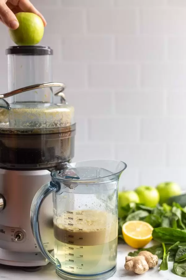 juicer with an apple going in the top to be juiced