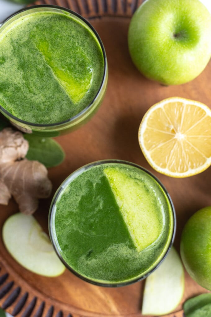 green juice in a small glass with another glass in the corner of the shot