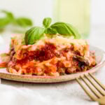 Vegan lasagna on a plate garnished with basil.