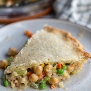 slice of chickpea pot pie filled with chickpeas and veggies with the full pie in the background