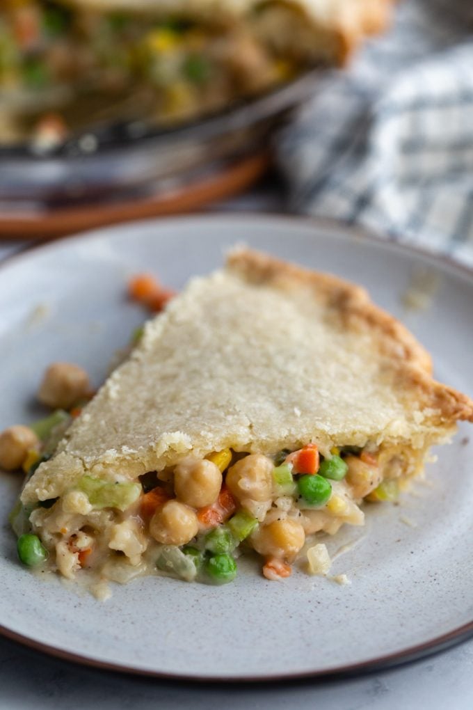 slice of chickpea pot pie filled with chickpeas and veggies with the full pie in the background