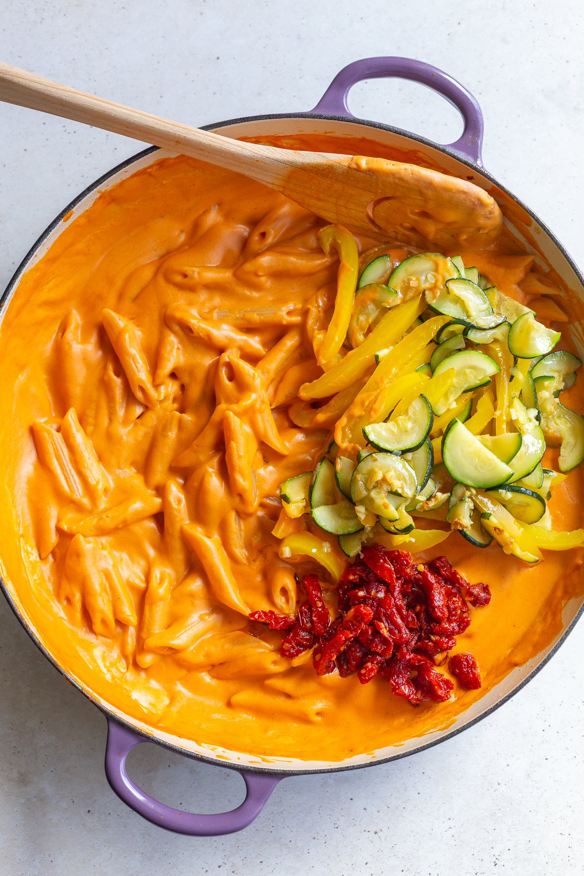 Stirring together sauce, veggies and penne pasta.