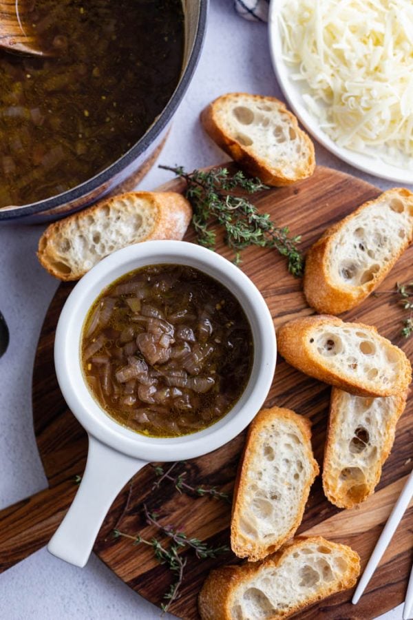 sopa de cebolla francesa en un bol blanco con pan tostado alrededor