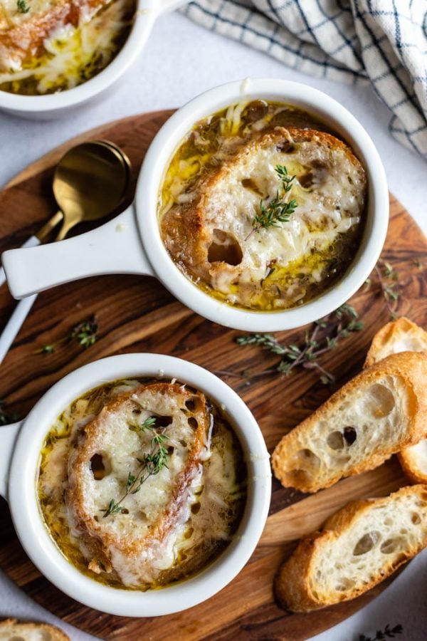 mehrere weiße Schüsseln Französische Zwiebelsuppe mit Brot und Käse obenauf