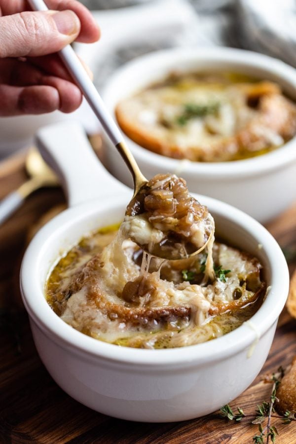 Foto cercana de cebollas caramelizadas saliendo de un bol de sopa de cebolla francesa