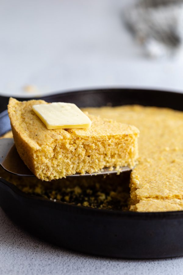 slice de pain de maïs sur une spatule étant tirée d'une poêle avec du beurre sur le dessus