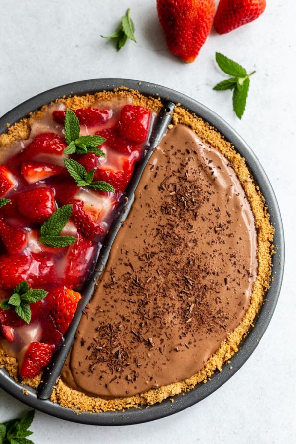 double sided "split decision pie" with a chocolate silken pie on one side and a fresh strawberry pie on the other. Fresh strawberries and mint are around the edges of the frame