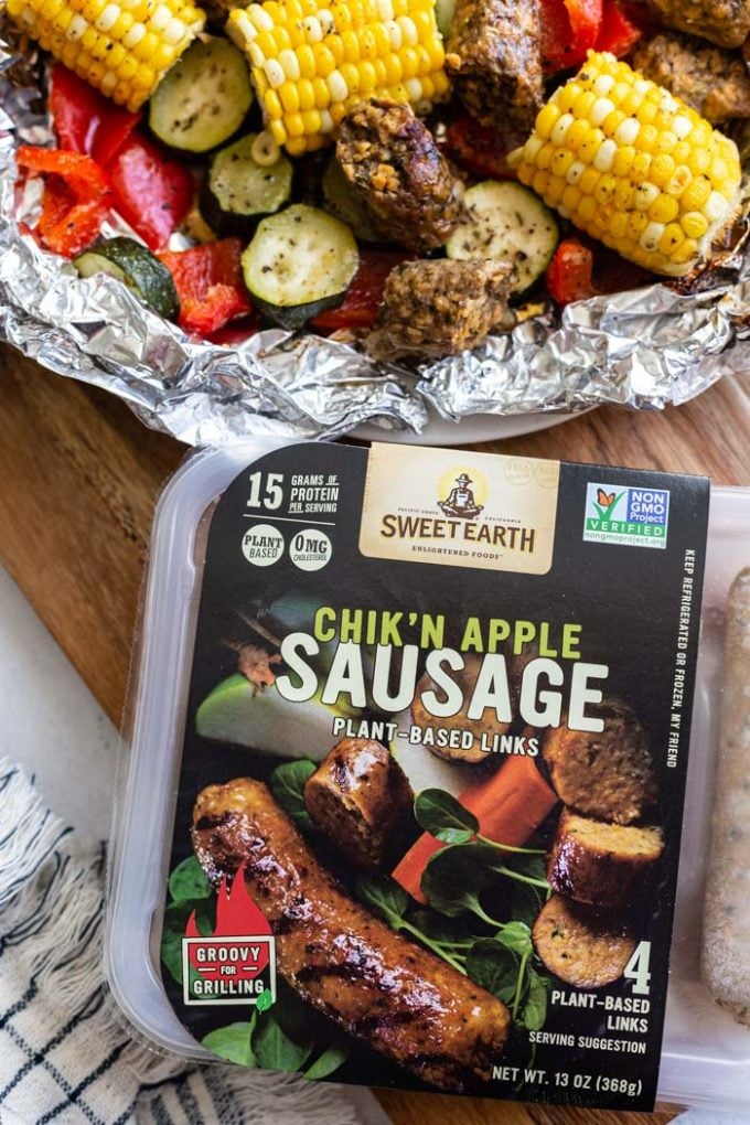 up close shot of Sweet Earth Chik'n Apple Sausage with a foil pack of food in the corner