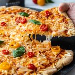 Hand picking up a slice of pizza.