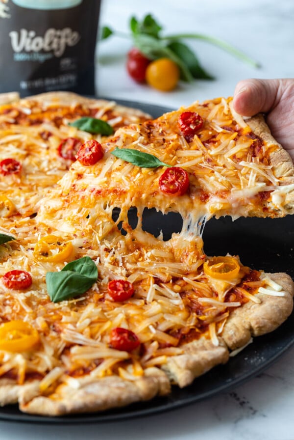 Hand picking up a slice of pizza.