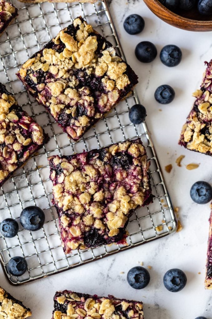 Blueberry crumble bars na stříbrném stojánku s borůvkami okolo