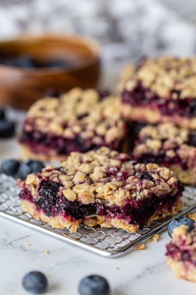 Blaubeer-Streusel-Riegel auf einem silbernen Gestell mit Blaubeeren herum