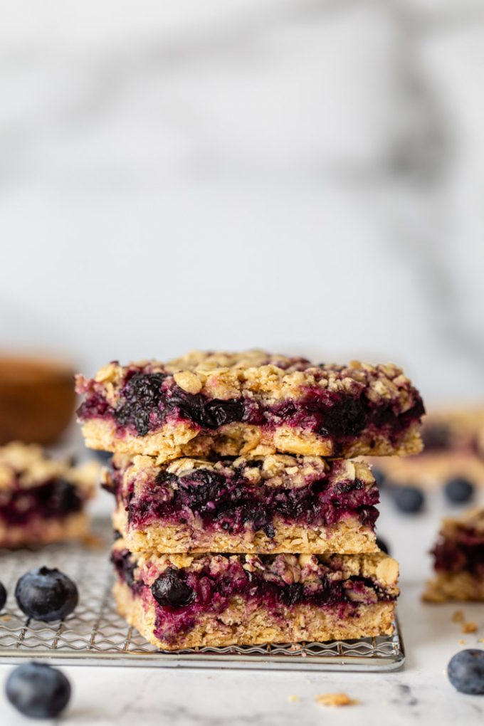 stack of blueberry crumble bars on a silver rack with blueberries around