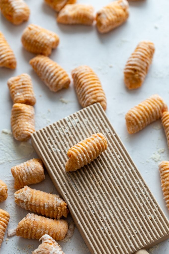 up close side shot of raw sweet potato gnocchi on a gnocchi board