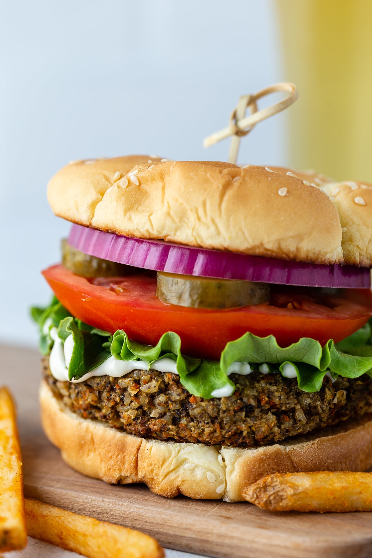 veggie burgers on a sesame seed bun with lettuce, tomato, pickles ,and red onion on it