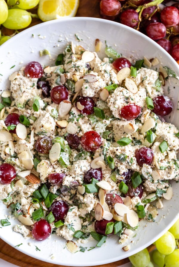 white bowl filled with "vegan chicken salad" that has chunks of tofu, veggies and grapes in it