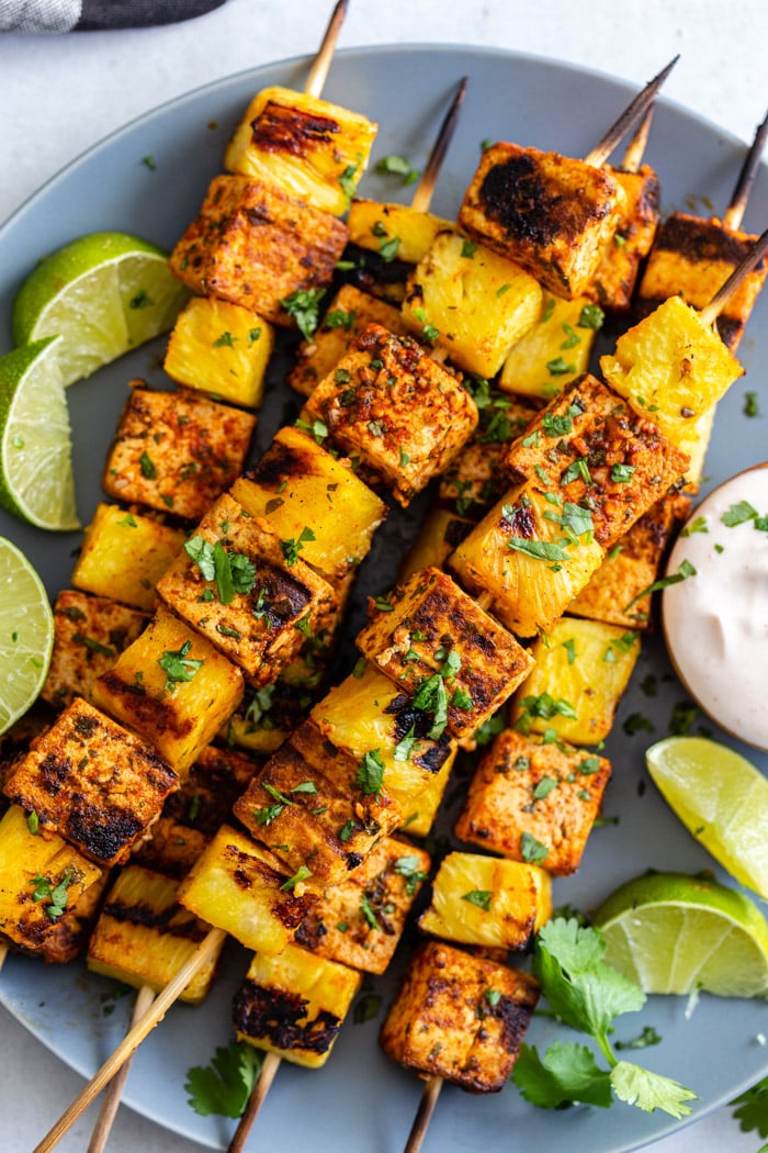 grilled skewers of tofu and pineapple on a light blue plate