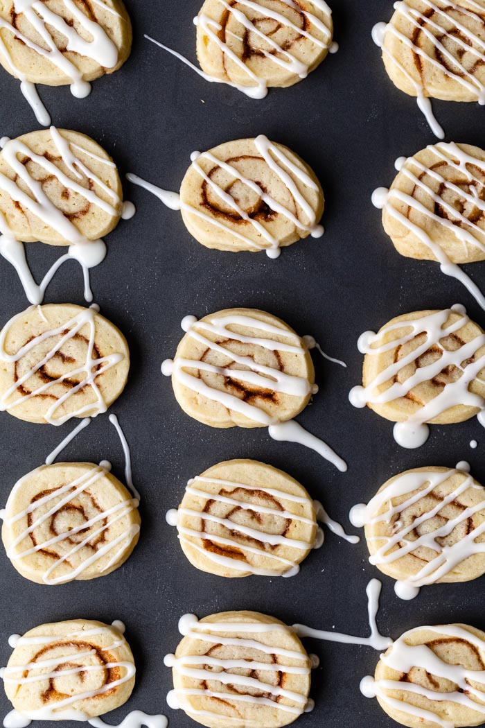 sheet pan filled with cinnamon roll cookies drizzled with icing