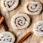 top down shot of cinnamon roll sugar cookies on parchment paper and drizzled with frosting