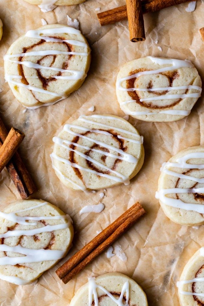top down shot of cinnamon roll sugar cookies on parchment paper and drizzled with frosting