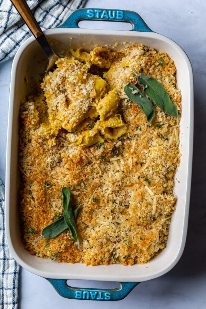 casserole de couleur sarcelle remplie de macaroni au fromage végétalien cuit au four et d'herbes fraîches