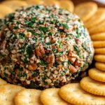 vegan cheeseball covered in chopped pecans and served with Ritz crackers
