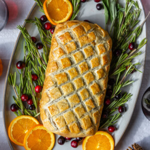 vegetarian wellington on a large platter surrounded by rosemary, orange, and fresh cranberries