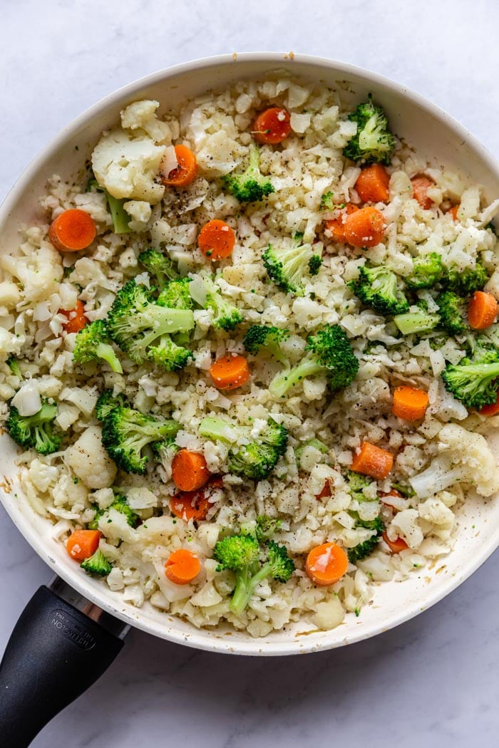 skillet with cauliflower fried rice that has broccoli and carrots in it
