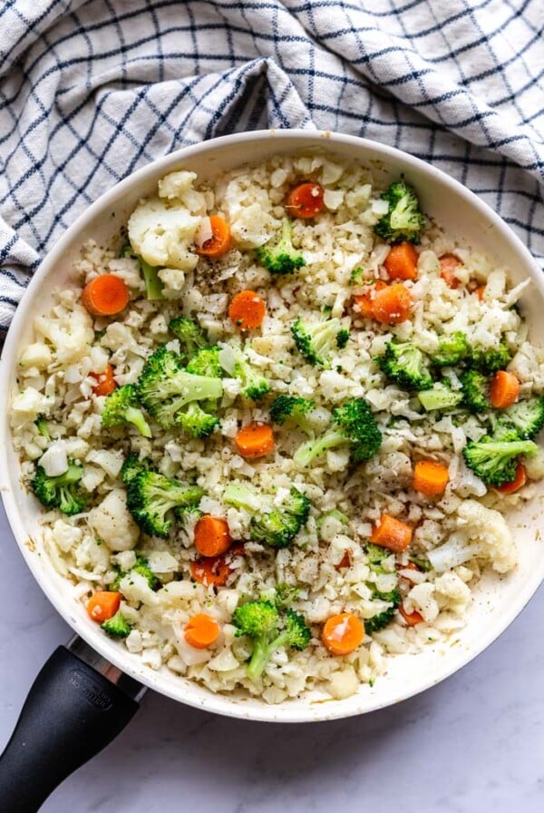 skillet with cauliflower fried rice that has broccoli and carrots in it