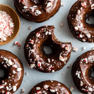 top down shot of chocolate donuts with a chocolate frosting and crushed peppermint on top