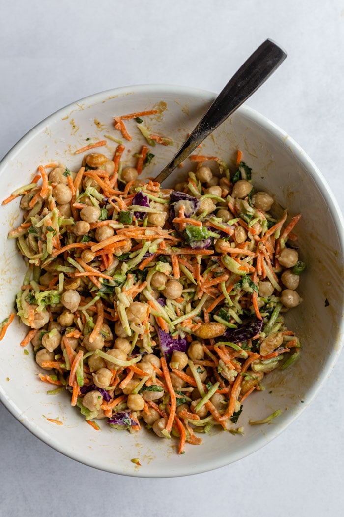 large white bowl filled with chickpeas and coleslaw mixed with a peanut sauce